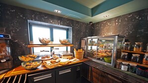 A bakery counter with various baked goods, a display case, and a window with blinds. - Hôtel Nota Bene (Montceau-les-Mines)