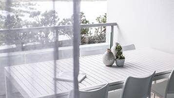 A white table with chairs and a vase on a balcony overlooking a body of water.