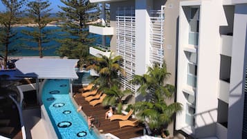 A resort pool area with lounge chairs and a view of the sea.