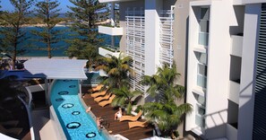A resort pool area with lounge chairs and a view of the sea.