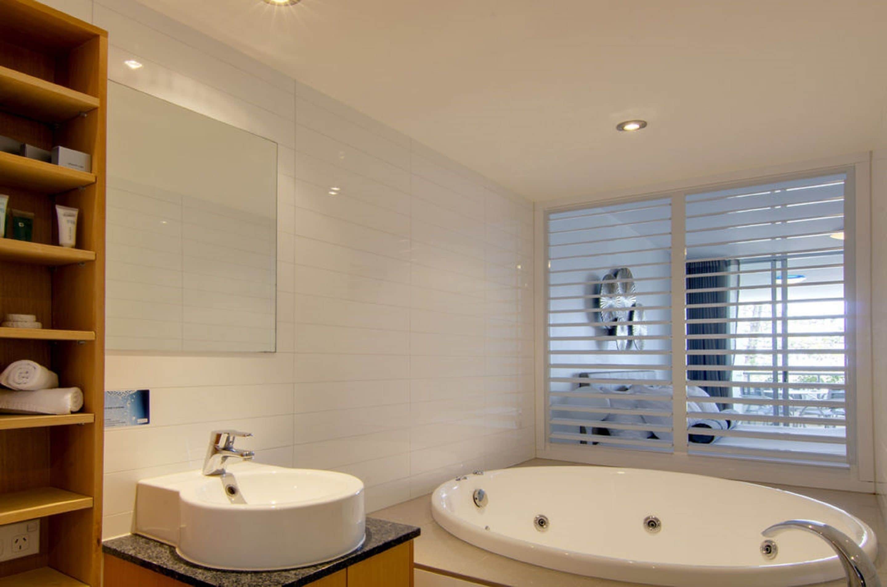 Een moderne badkamer met een vrijstaand bad, een wastafelmeubel met een wastafel en een grote spiegel.