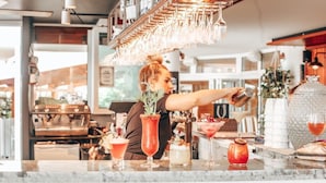 Un espace bar avec un barman préparant des boissons, une machine à café et divers outils et verres de bar.