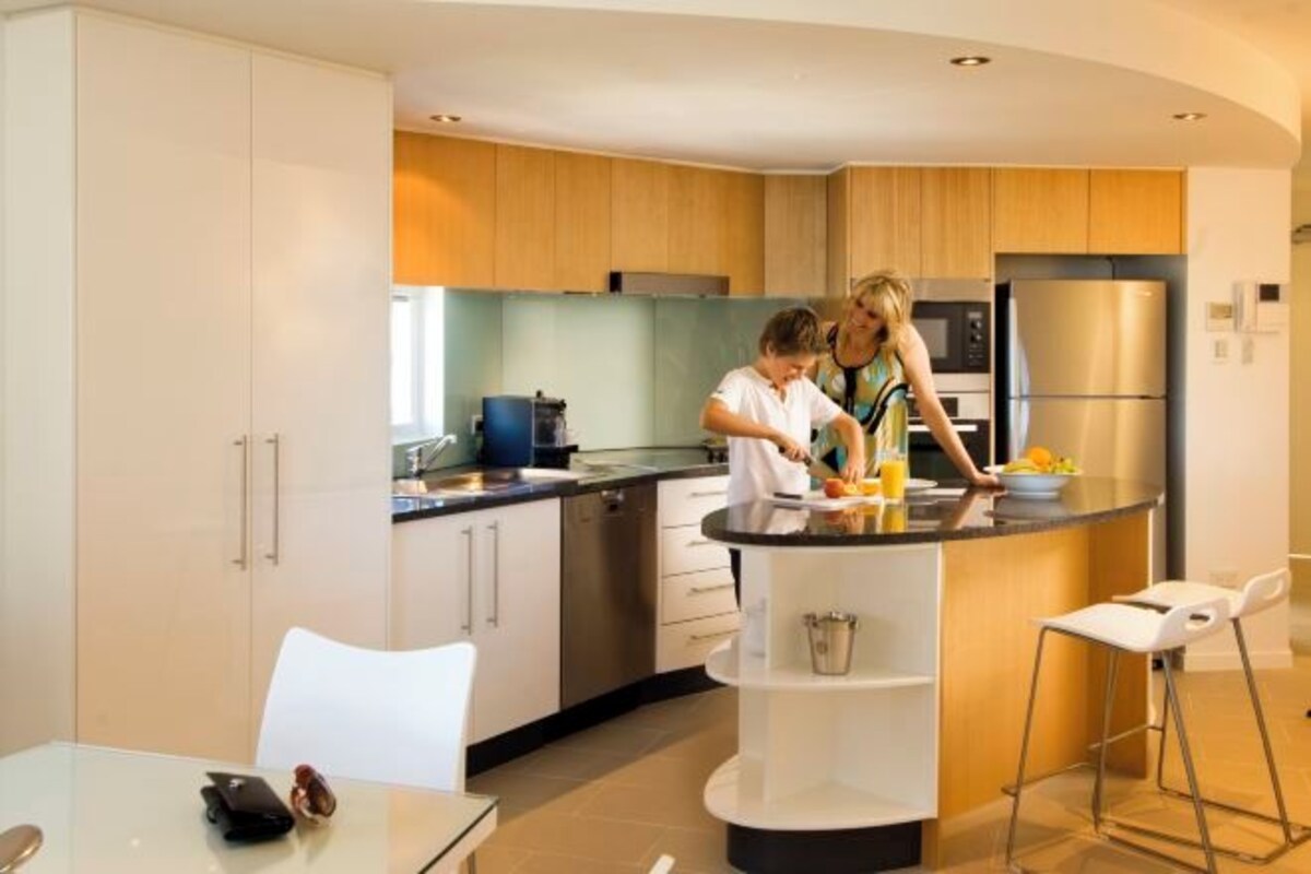 A modern kitchen with a central island, stainless steel appliances, and wooden cabinetry.