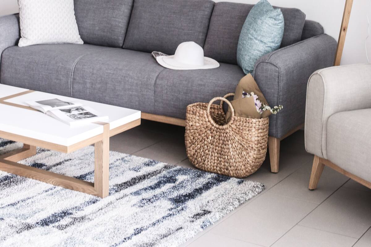 A modern living room with a grey sofa, a white coffee table, and two framed abstract paintings on the wall.