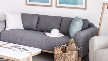 A modern living room with a grey sofa, a white coffee table, and two framed abstract paintings on the wall.