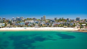 Un paysage urbain côtier avec une plage, des immeubles de grande hauteur et un ciel bleu dégagé.