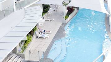 A pool area with lounge chairs and a sign indicating toilets.