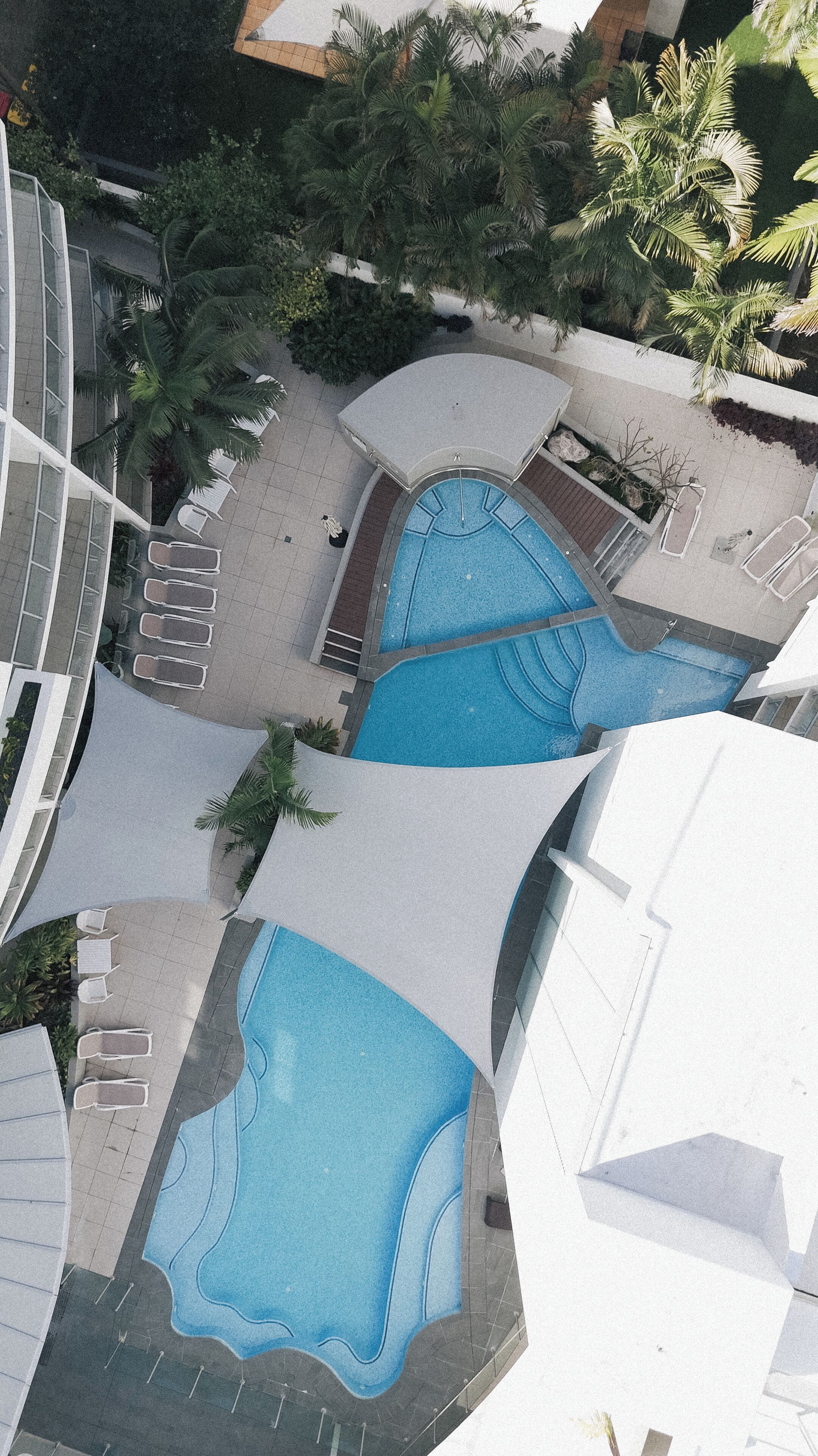 A rooftop pool area with multiple pools and lounge chairs.