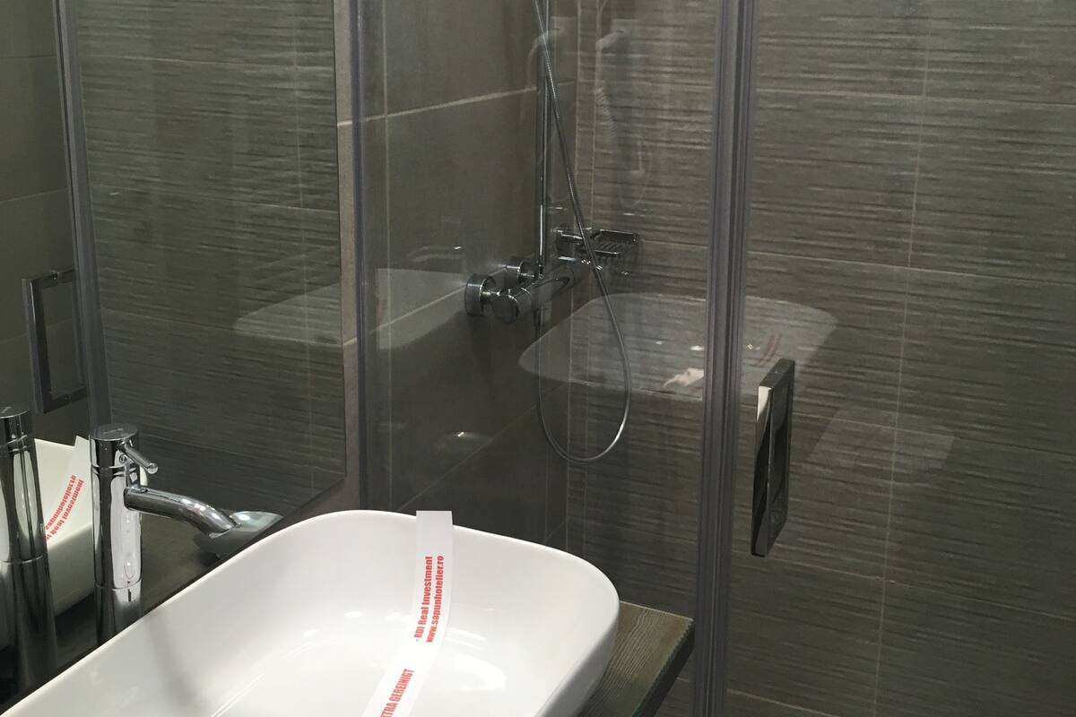 Ein modernes Badezimmer mit einer Duschkabine aus Glas, einem weißen Waschbecken und einem Spiegel.