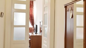 Un pasillo con un aparador de madera y un espejo, que conduce a una habitación con una cama y una ventana con cortinas.