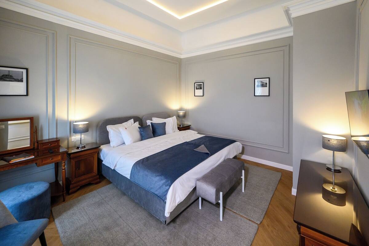 Ein ordentlich eingerichtetes Schlafzimmer mit Bett, Nachttischen, Schreibtisch und Stuhl.
