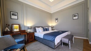 Un dormitorio con una cama grande, mesitas de noche, una silla y un escritorio.