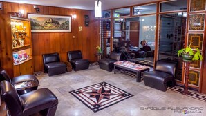 Um hall com poltronas de couro, uma mesa de centro, um quadro emoldurado e um vaso de planta.