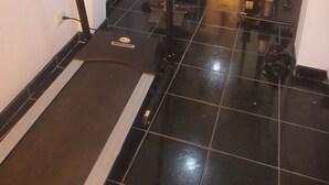Uma academia em casa com esteira, elíptica e banco de musculação.