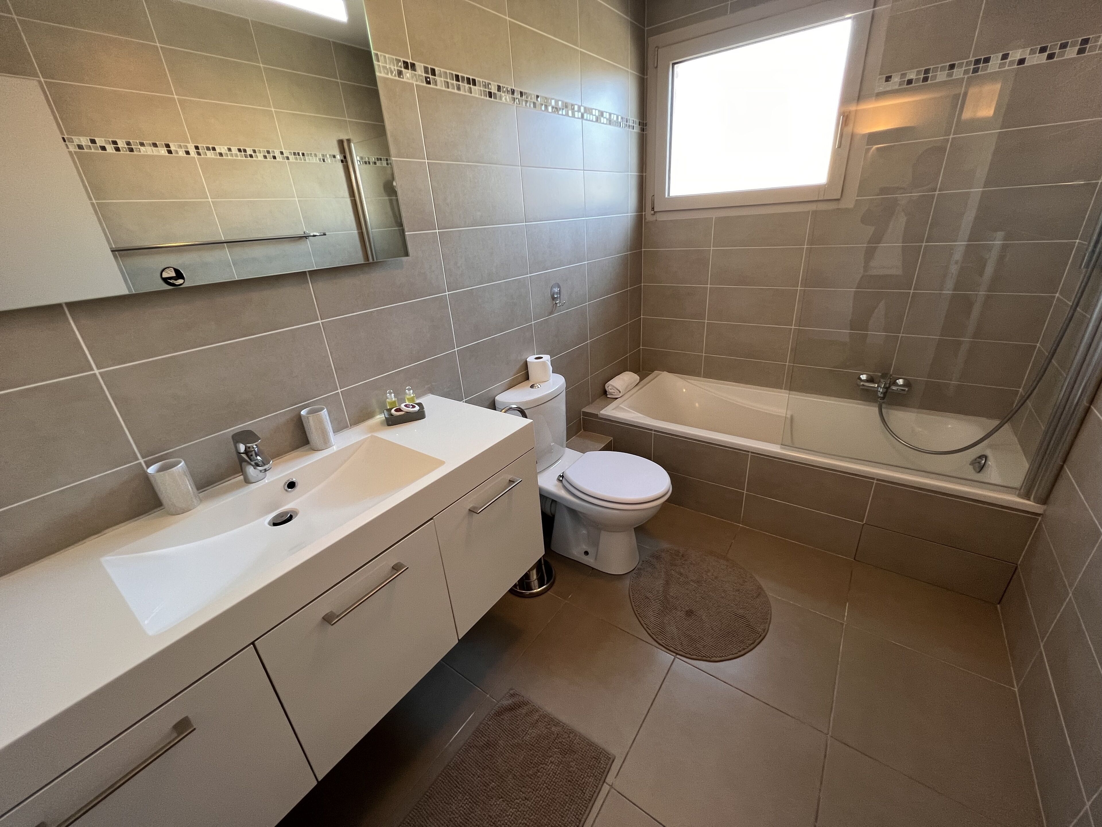 Een moderne badkamer met een wastafel, toilet en bad.