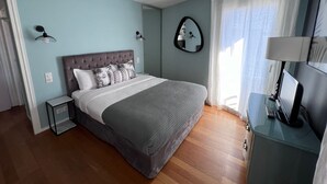 A bedroom with a bed, bedside tables, a mirror, and a desk with a lamp. - Riviera Eden Palace (Cannes)