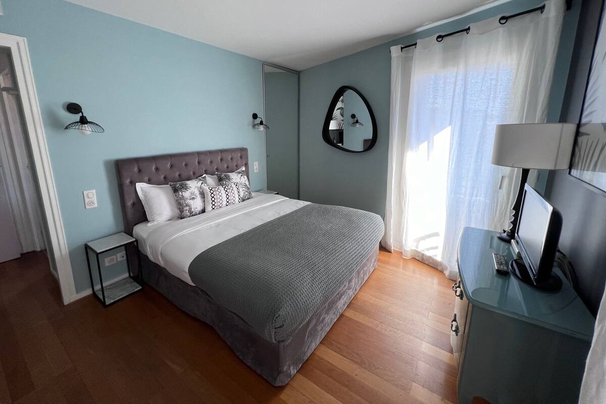 A bedroom with a bed, bedside tables, a mirror, and a desk with a lamp.