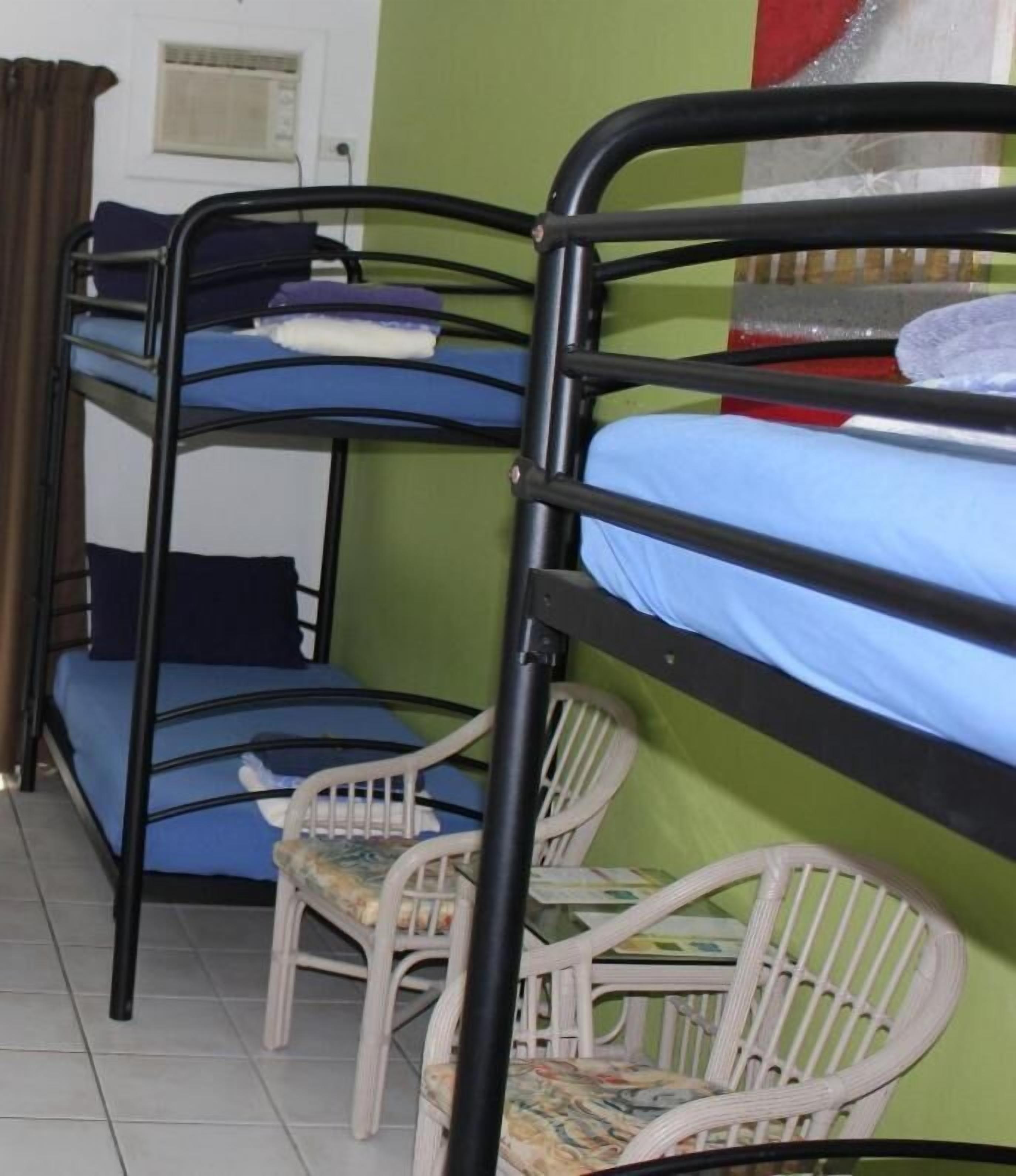 A bunk bed room with two white wicker chairs and a window with curtains.
