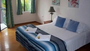 A bedroom with a bed, curtains, a lamp, and two wall-mounted flower paintings.