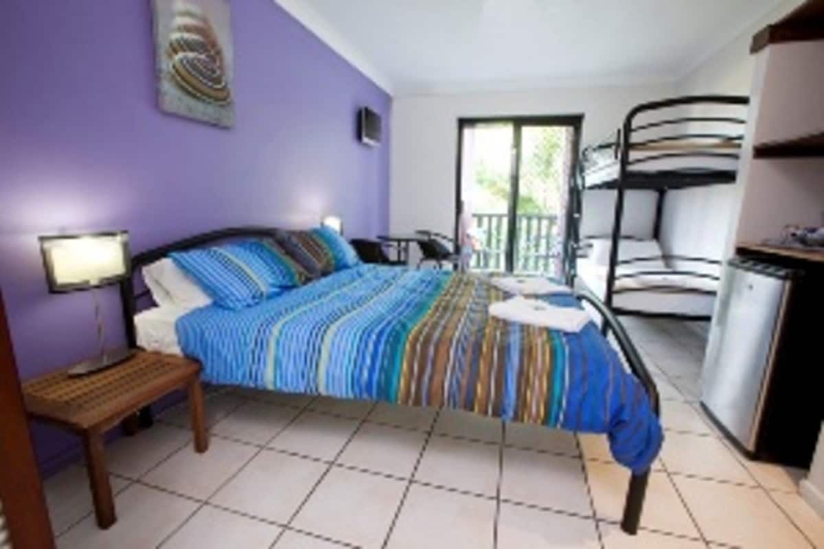 A room with a bed, a desk, a chair, and a bunk bed.