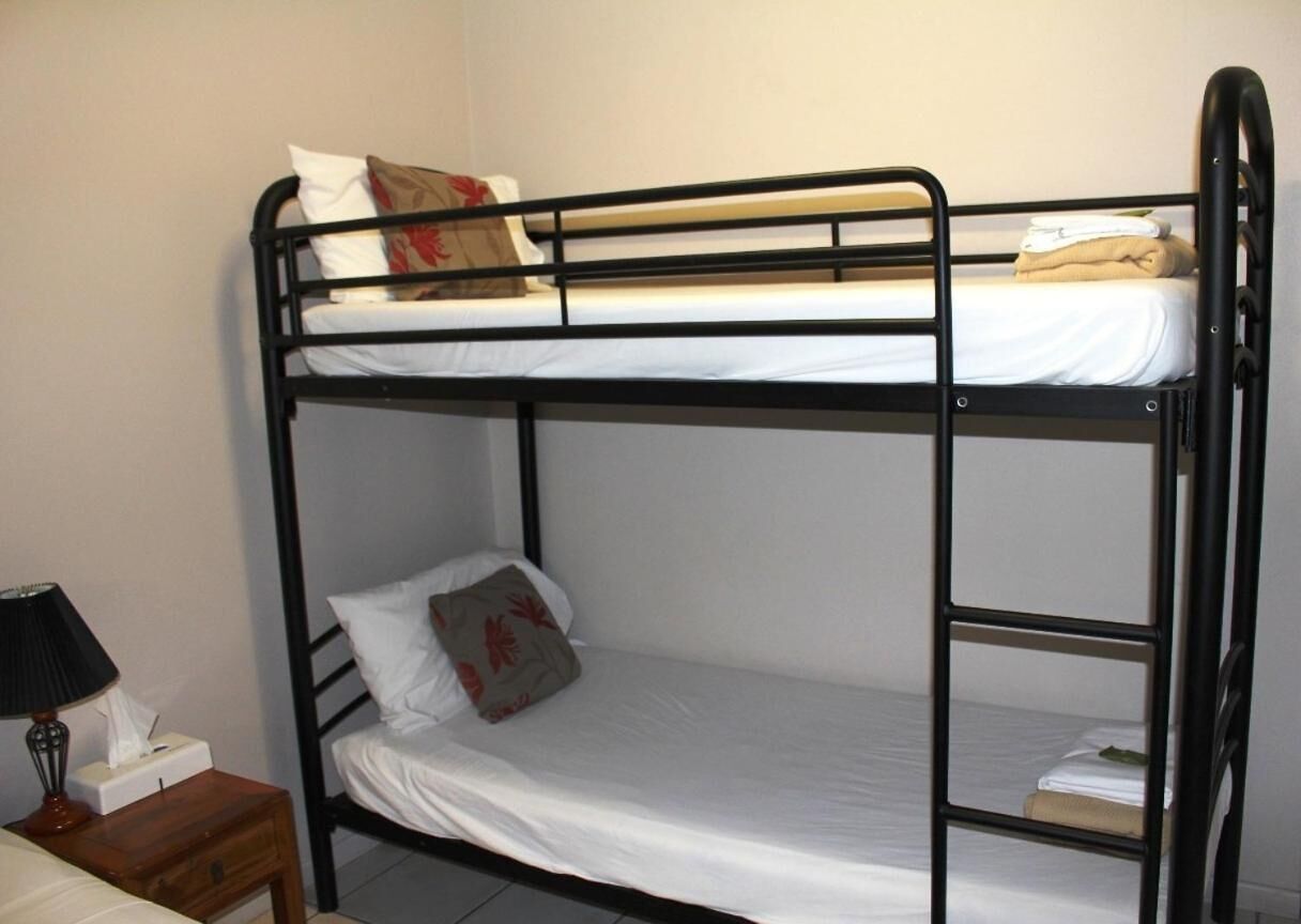 A bunk bed with a nightstand and a lamp.