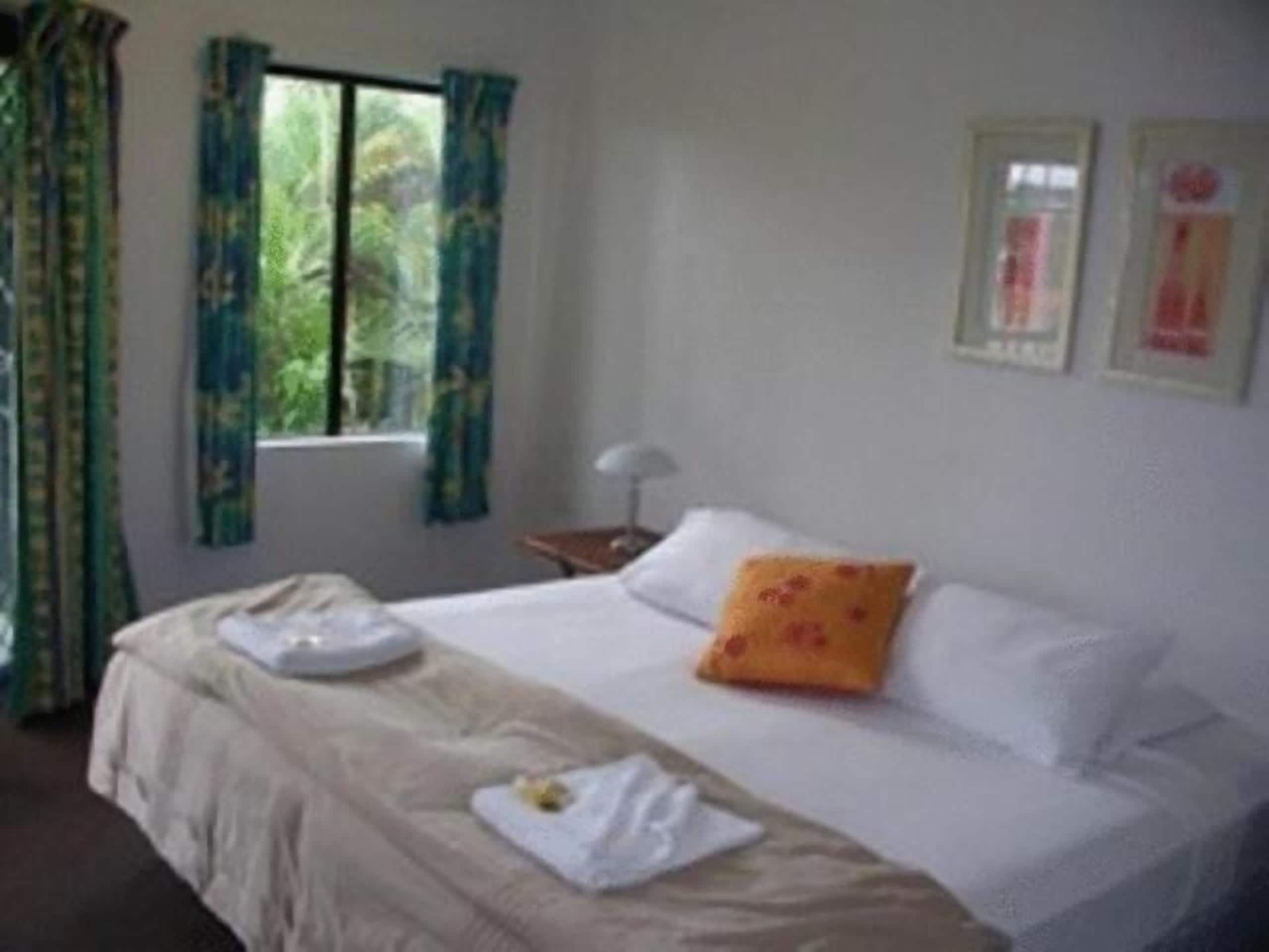 A hotel room with a bed, a window with curtains, a bedside table, and a lamp.