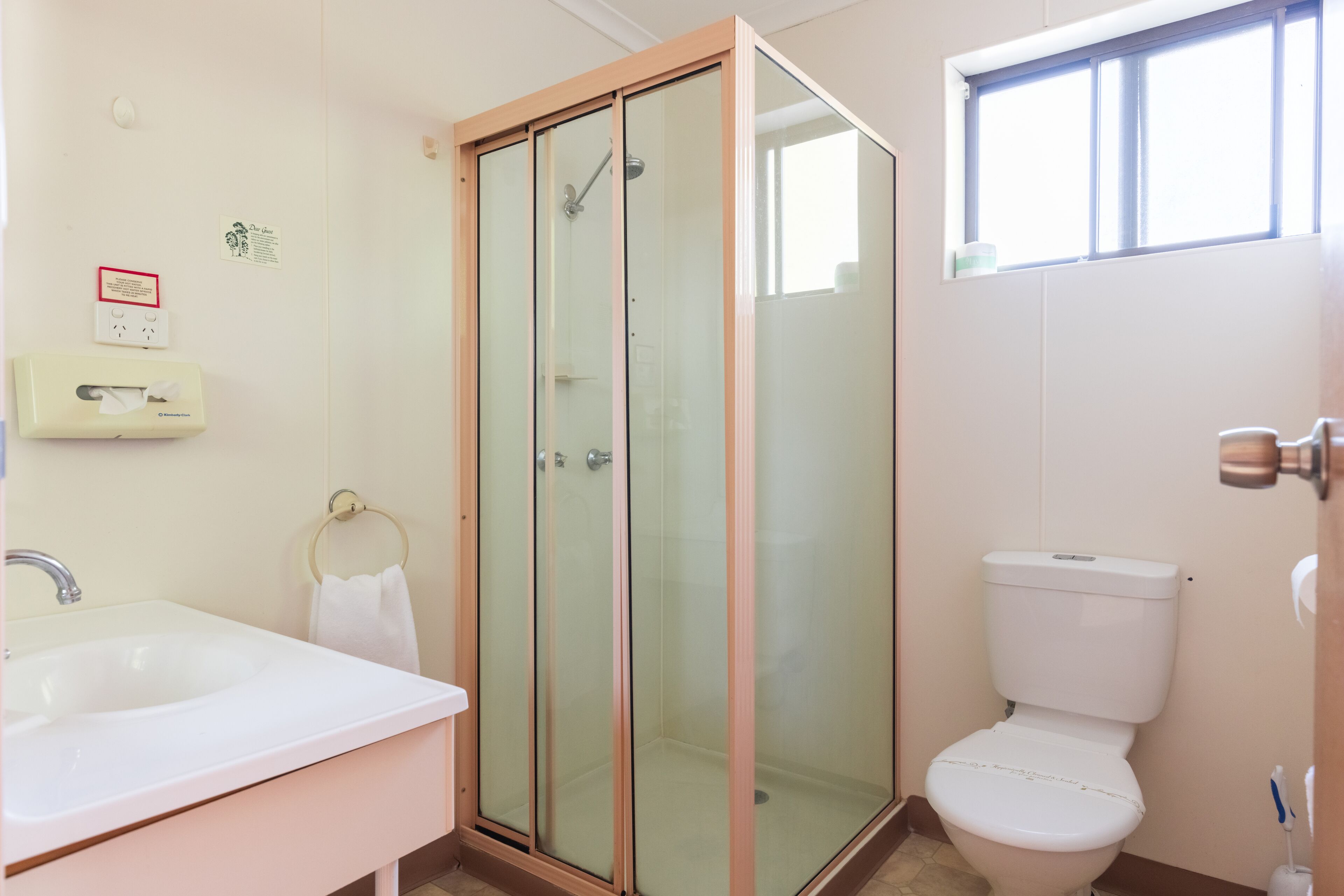 Un baño con cabina de ducha de vidrio, un lavamanos blanco y un inodoro.