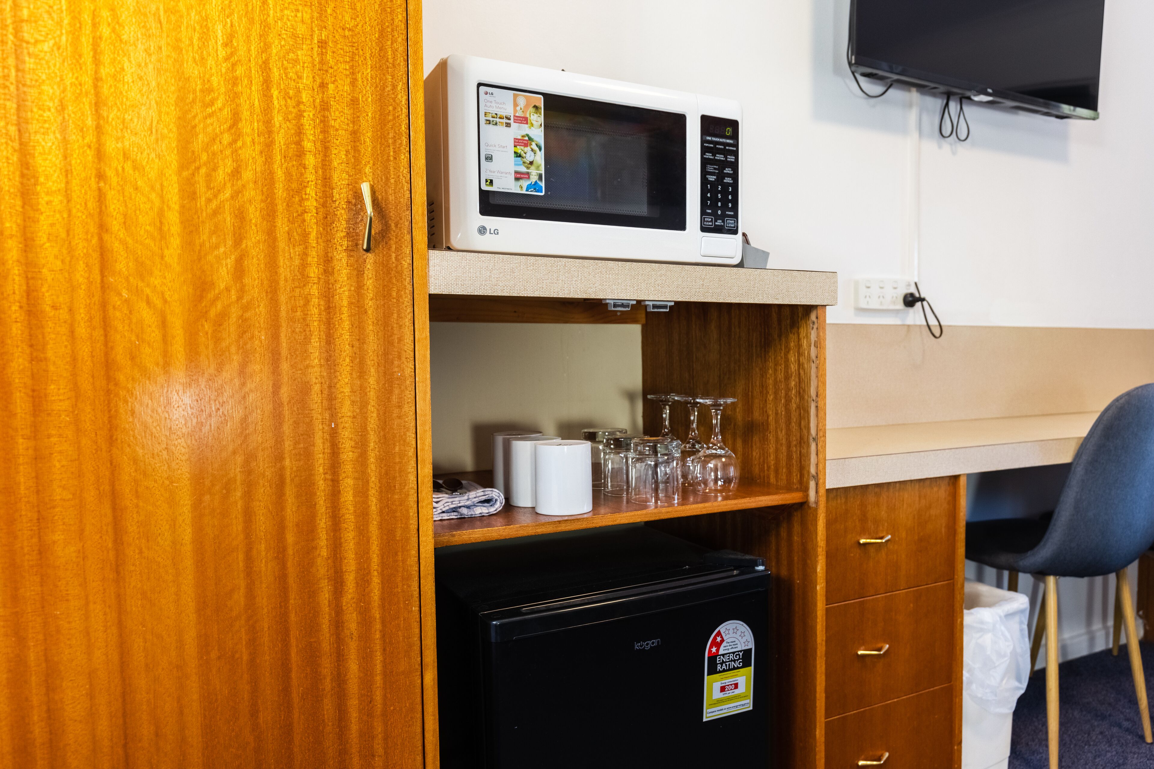 A compact kitchenette with a microwave, a small refrigerator, and a wooden cabinet.