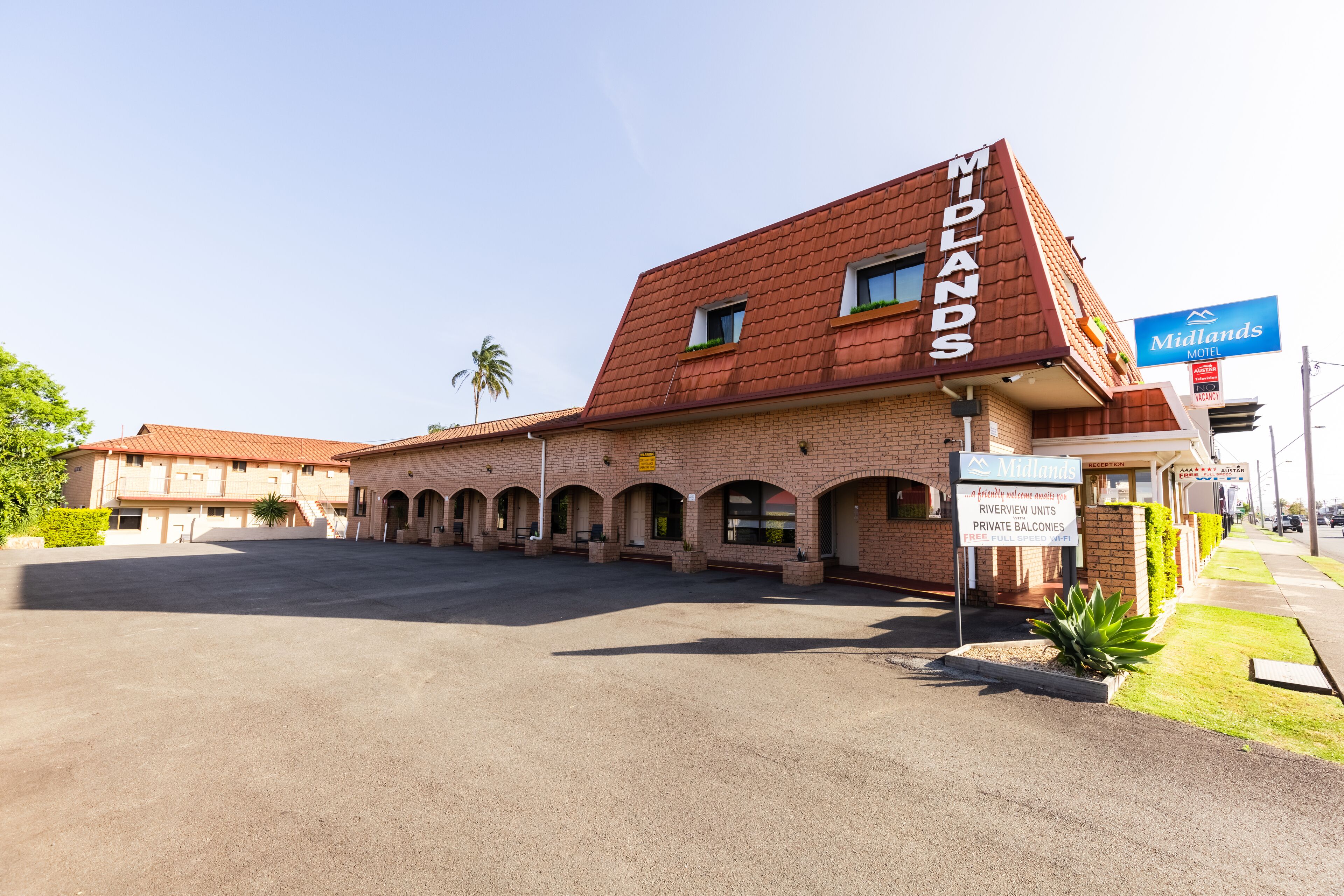 A brick building with a sign reading "Midlands Motel" and "Riverview Units Private Balconies."