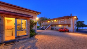 A motel with a guest laundry facility, a covered parking area, and a red car parked in front.