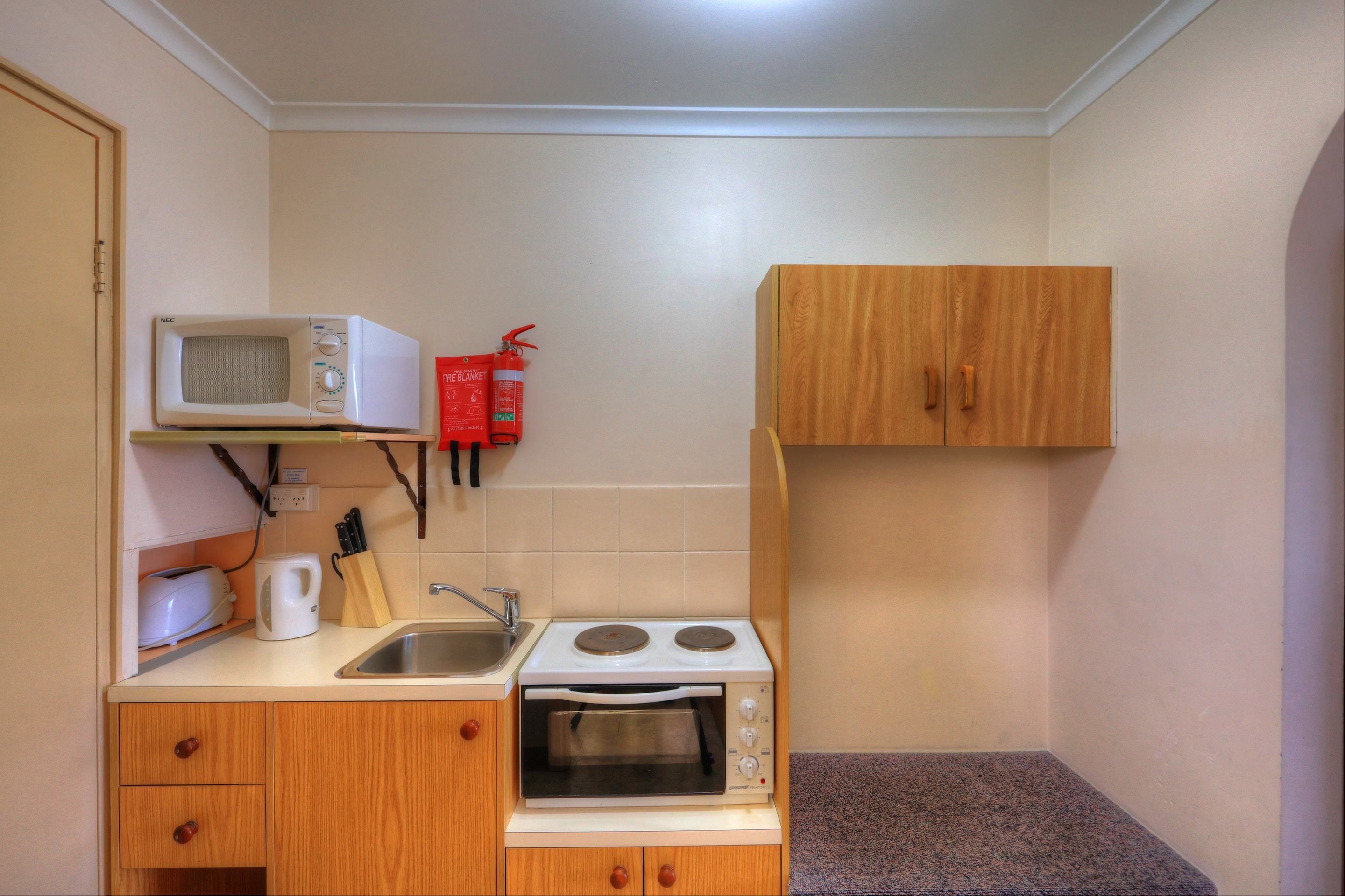 Una kitchenette funcional con microondas, tostadora y lavamanos.