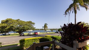A parking area with cars, a body of water, and a building in the background.