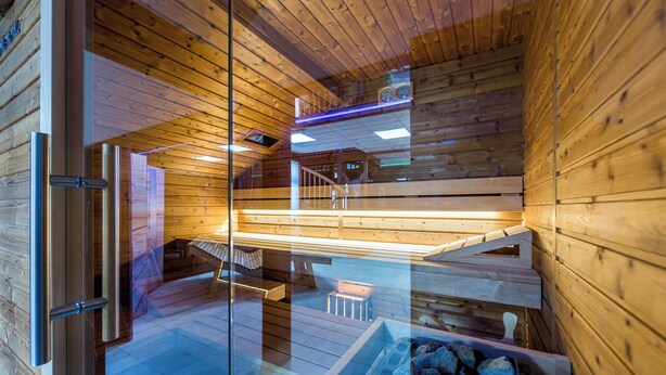 Interior de una cabaña de madera con puerta de cristal, una escalera de madera y una zona de estar.