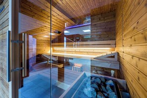 Interior de una cabaña de madera con puerta de cristal, una escalera de madera y una zona de estar.
