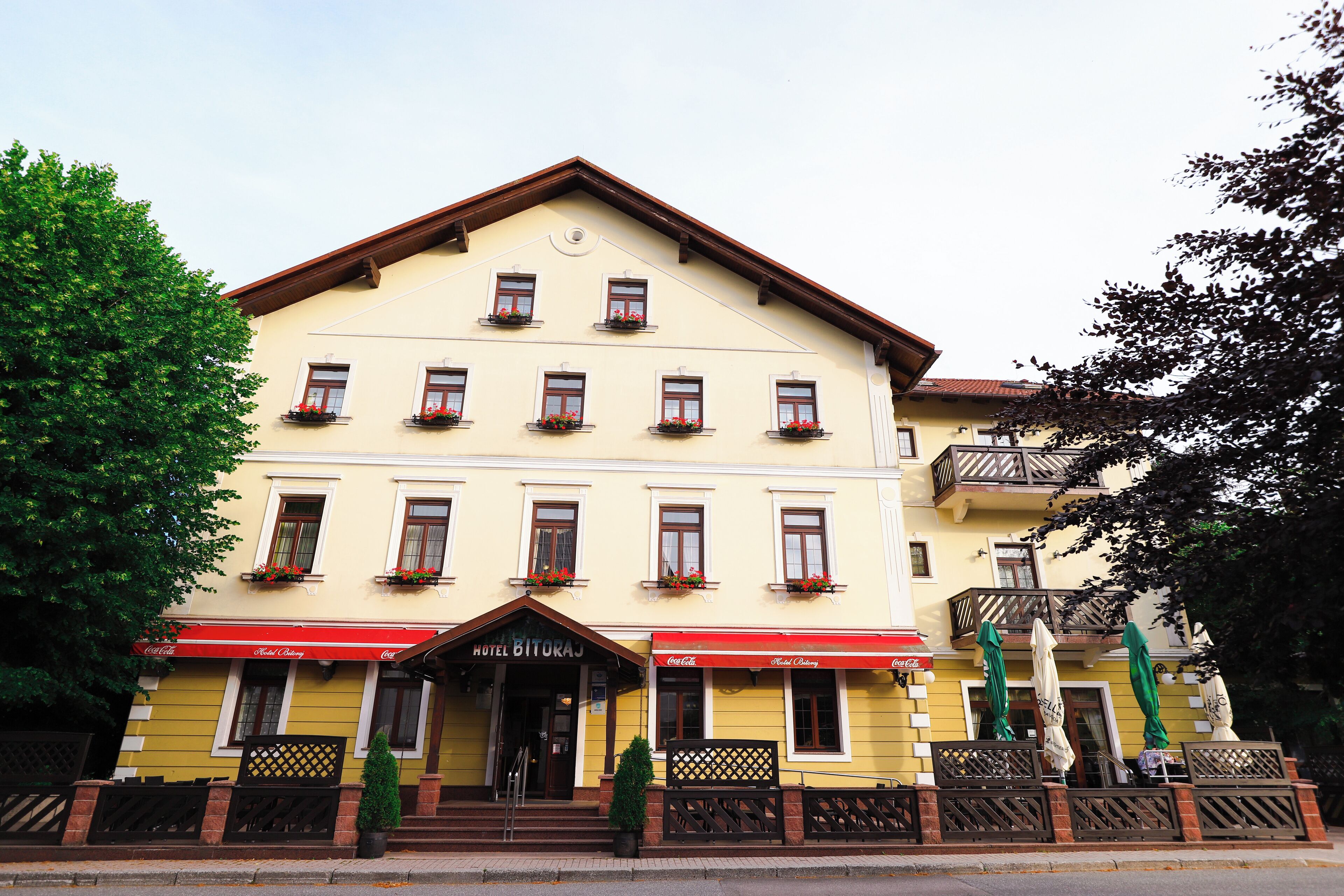A two-story hotel with a yellow facade, multiple windows, and a red awning.