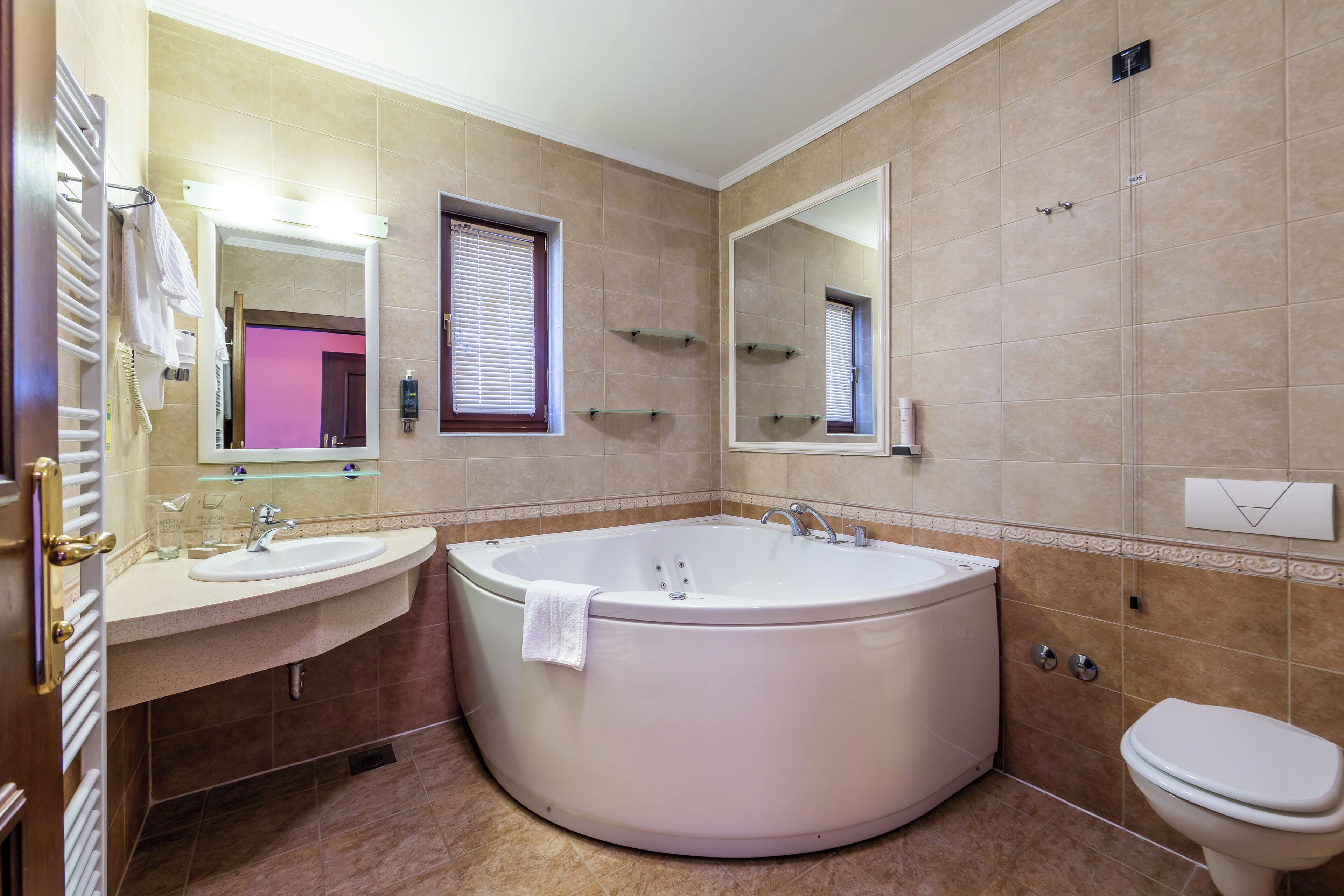 Une salle de bain avec une baignoire, deux lavabos, des toilettes et un grand miroir.