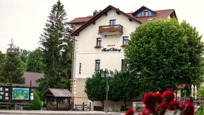 Un hotel con un balcón, un cartel que dice "Hotel Bitomi" y vistas a una calle con un banco y una estructura de madera.
