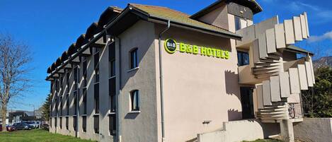 Un hotel B&B con un diseño arquitectónico único, que presenta un tejado inclinado y una escalera destacada que conduce a la entrada.