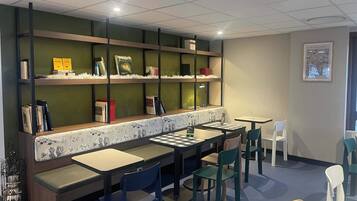 A library or reading area with bookshelves, seating, and tables.