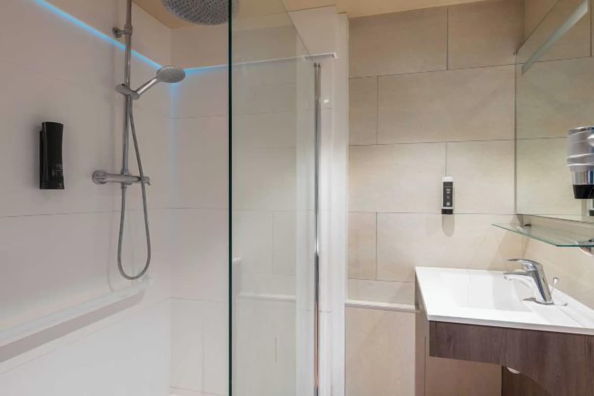 Ein modernes Badezimmer mit Duschkabine aus Glas, einem weißen Waschbecken und einem Spiegel.