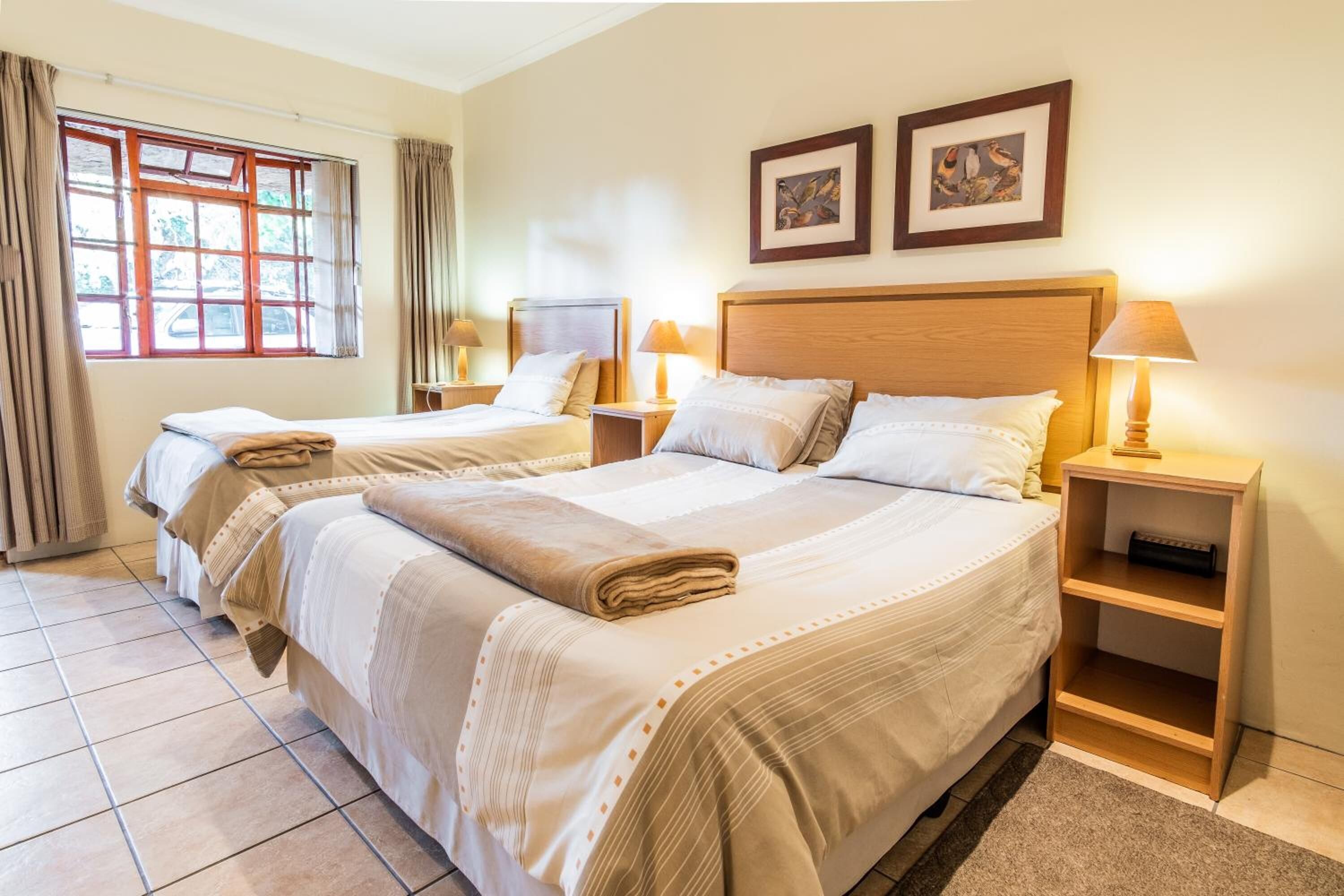 Habitación de hotel con dos camas, un ventanal grande y vistas al exterior.