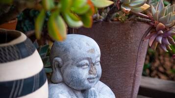 A stone Buddha statue, a striped ceramic bowl, and a potted succulent plant on a wooden surface.