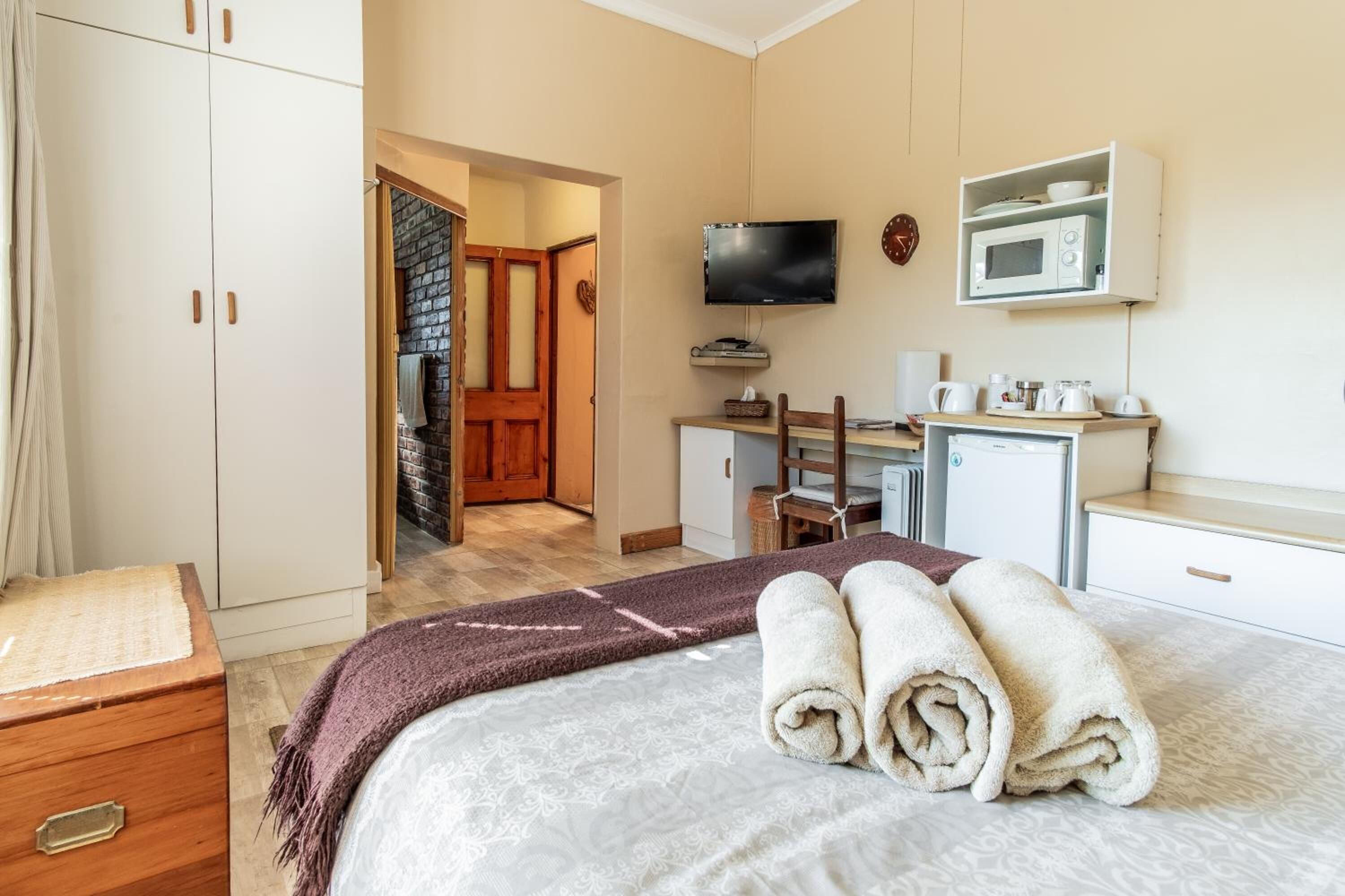 A hotel room with a bed, a desk, a television, a microwave, and a wardrobe.