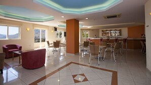 A spacious lobby with a bar area, seating arrangements, and large windows offering views. - Lindos Nest (Rhodes)