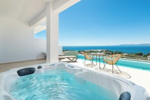 A hot tub with a clear view of the sea and mountains in the background.
