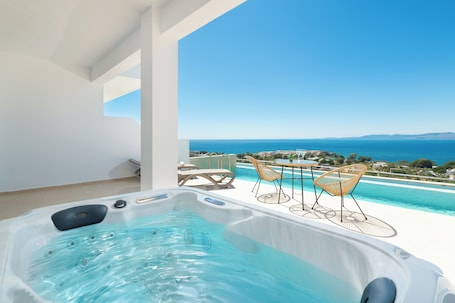 A hot tub with a clear view of the sea and mountains in the background.