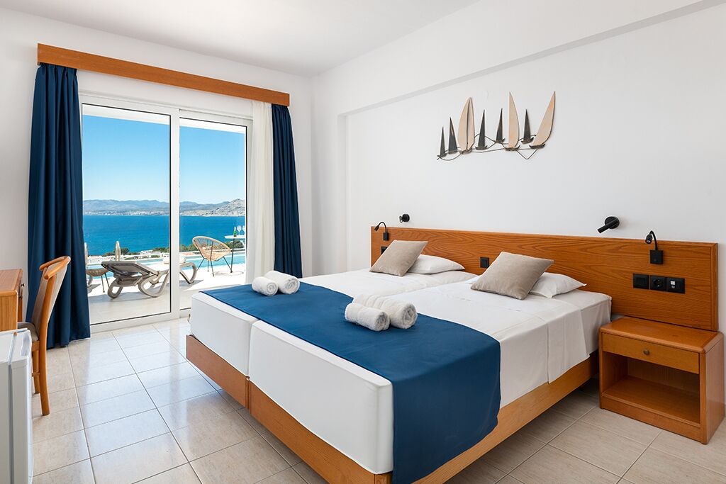 Uma cama de casal com colcha azul, cabeceira de madeira e mesa de cabeceira.