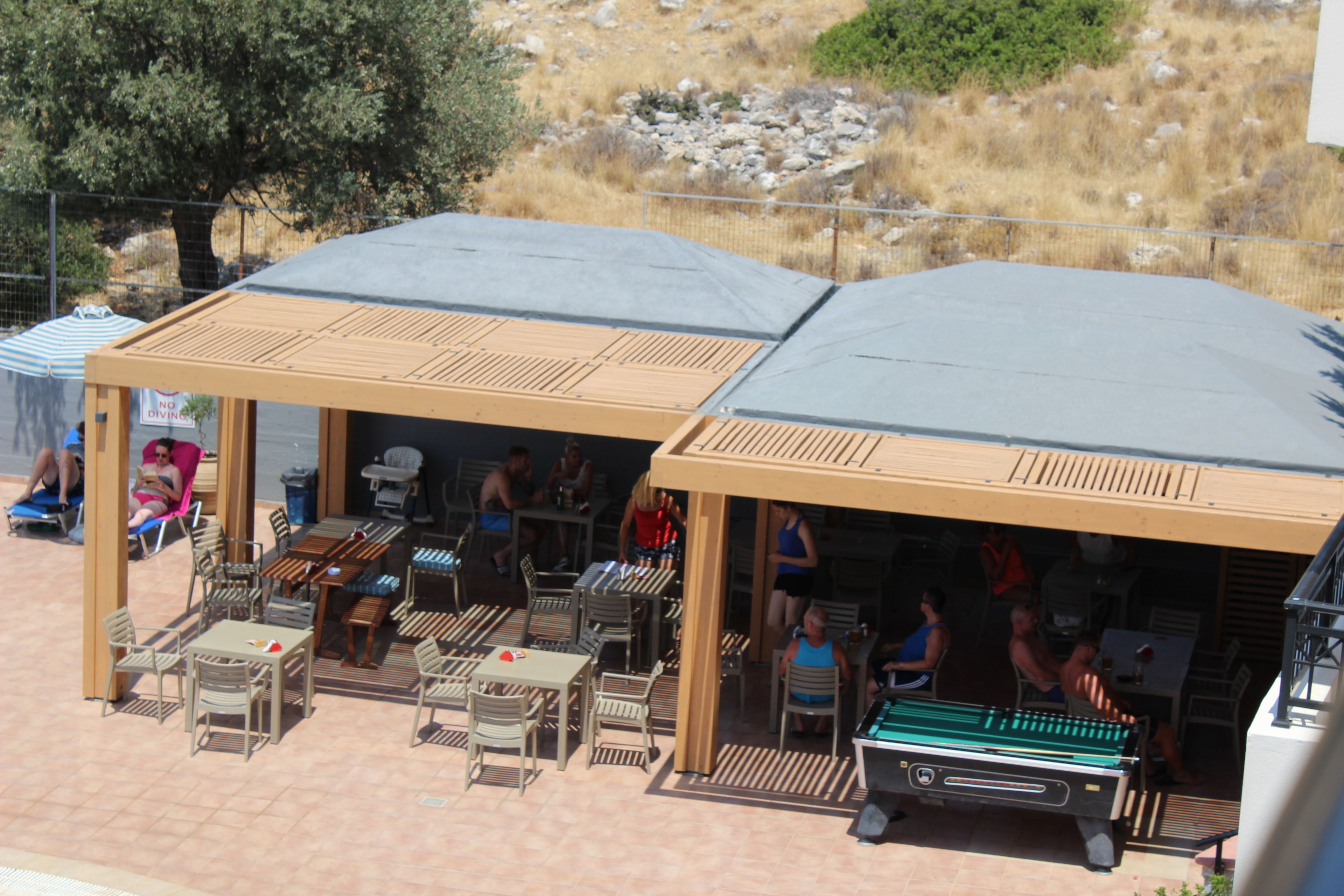 An outdoor patio area with tables and chairs, a pool table, and a covered seating area.