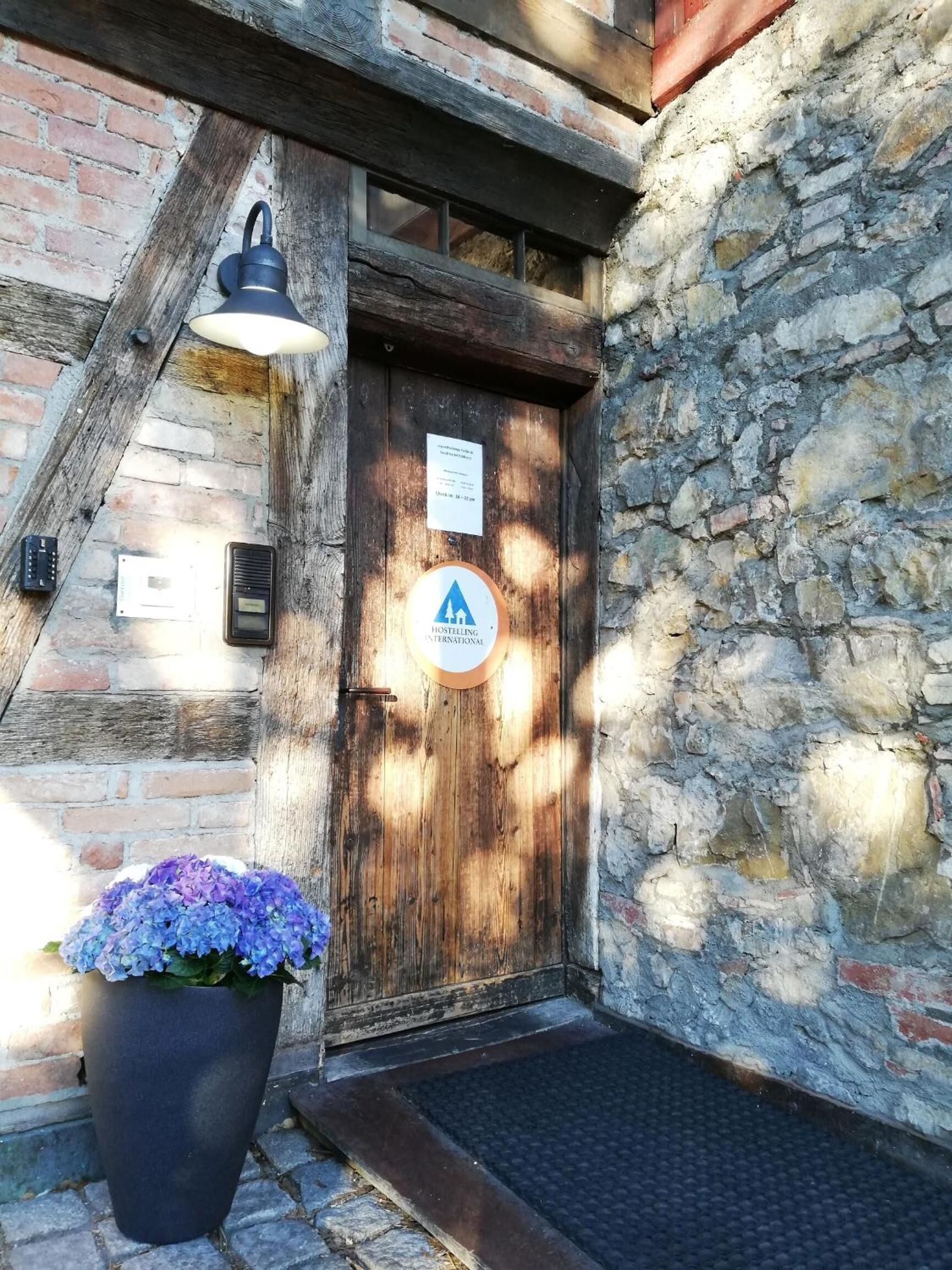 A rustic wooden door with a sign indicating a hostel.