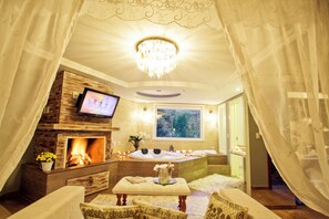 A luxurious room with a fireplace, a large window, a bathtub, and a television.